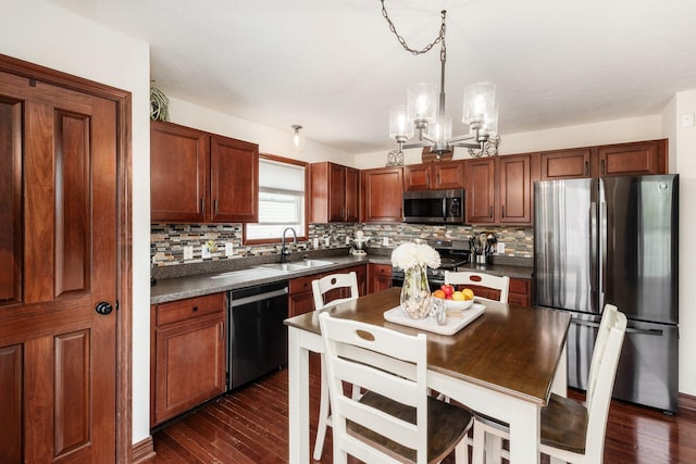 kitchen featuring backsplash, dark countertops, appliances with stainless steel finishes, and a sink