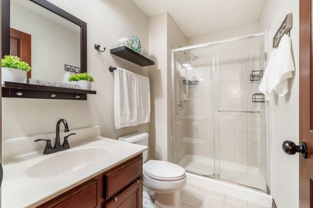 full bath featuring tile patterned flooring, vanity, toilet, and a stall shower