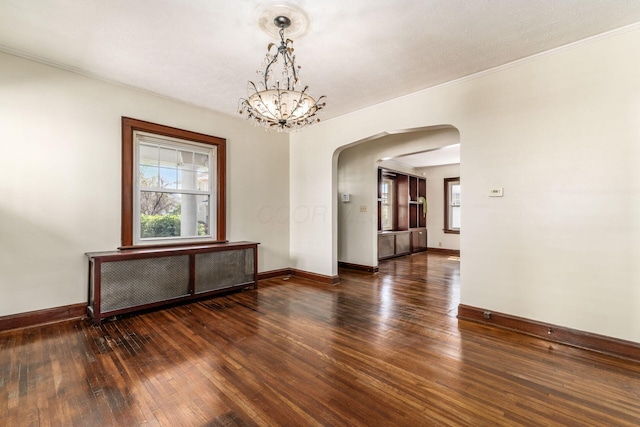 629 Hilltonia Ave, Columbus, OH 43223 - empty room with crown molding, a chandelier, arched walkways, baseboards, and dark wood-type flooring