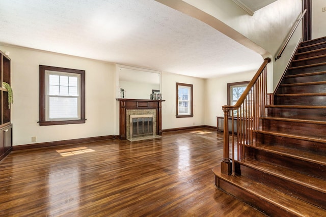 629 Hilltonia Ave, Columbus, OH 43223 - unfurnished living room with dark wood finished floors, a wealth of natural light, stairs, and baseboards