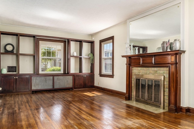 629 Hilltonia Ave, Columbus, OH 43223 - unfurnished living room featuring radiator, dark wood finished floors, a tiled fireplace, baseboards, and crown molding
