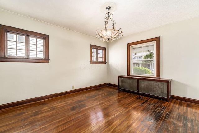 629 Hilltonia Ave, Columbus, OH 43223 - empty room featuring a notable chandelier, radiator heating unit, baseboards, ornamental molding, and dark wood-type flooring