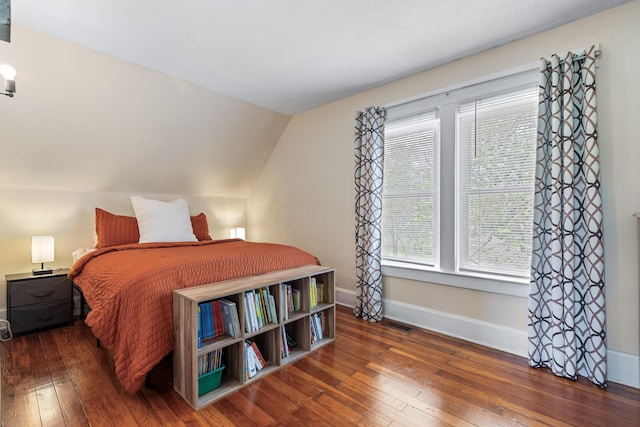 bedroom with baseboards, lofted ceiling, visible vents, and hardwood / wood-style floors