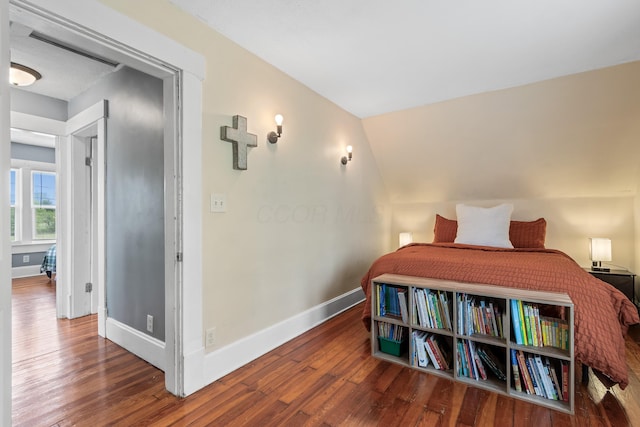 bedroom featuring baseboards, vaulted ceiling, and wood finished floors