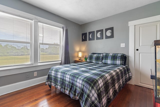 bedroom featuring baseboards, hardwood / wood-style flooring, and a closet