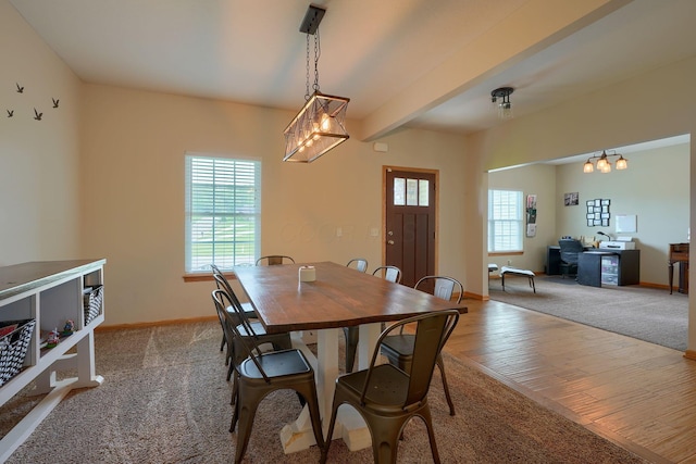 carpeted dining room featuring baseboards, wood finished floors, and a chandelier