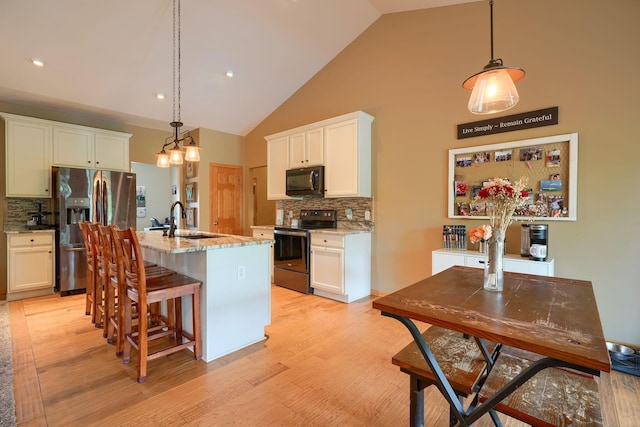 kitchen with a sink, decorative backsplash, electric range oven, stainless steel fridge, and black microwave