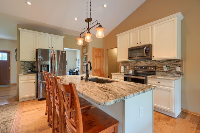 kitchen with tasteful backsplash, a sink, appliances with stainless steel finishes, light wood-style floors, and light stone countertops