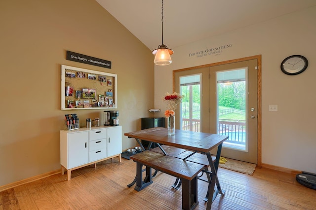 dining room with baseboards, high vaulted ceiling, and light wood-style floors