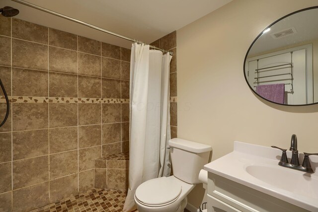 bathroom with visible vents, tiled shower, toilet, and vanity
