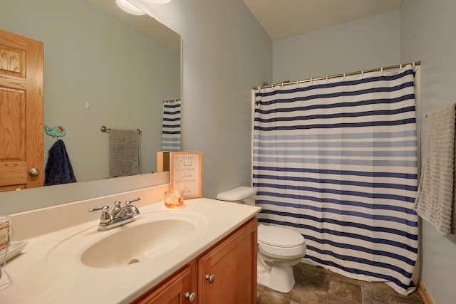 bathroom featuring stone finish flooring, a shower with shower curtain, toilet, and vanity