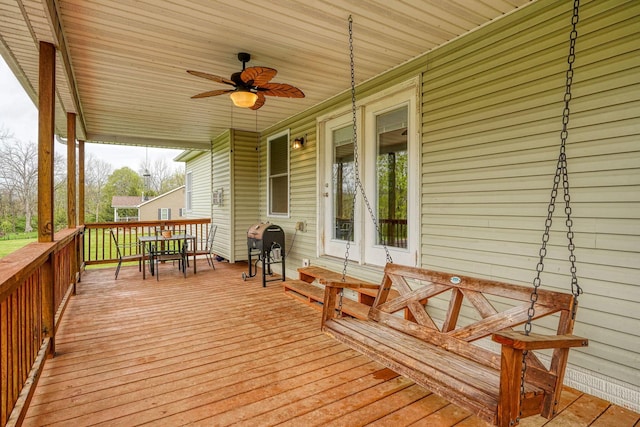 deck featuring outdoor dining space, ceiling fan, and a grill