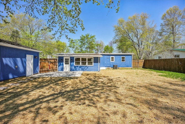 rear view of property with a fenced backyard, a lawn, and cooling unit