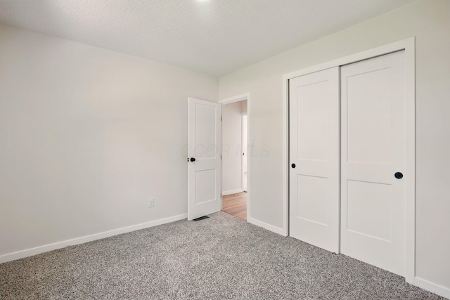 unfurnished bedroom with baseboards, carpet, and a closet
