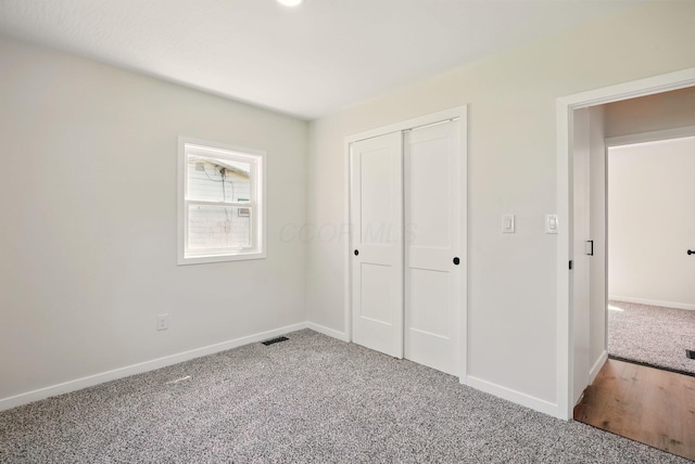 unfurnished bedroom featuring carpet floors, baseboards, and a closet
