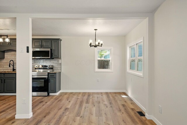 kitchen featuring visible vents, light wood-type flooring, gray cabinets, appliances with stainless steel finishes, and a notable chandelier