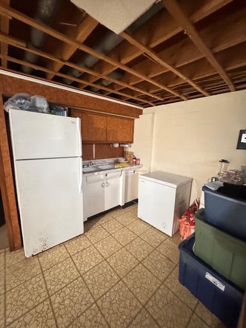 kitchen featuring freestanding refrigerator, fridge, white cabinetry, light flooring, and light countertops
