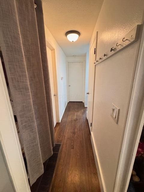 hall featuring dark wood-style flooring, baseboards, and a textured ceiling