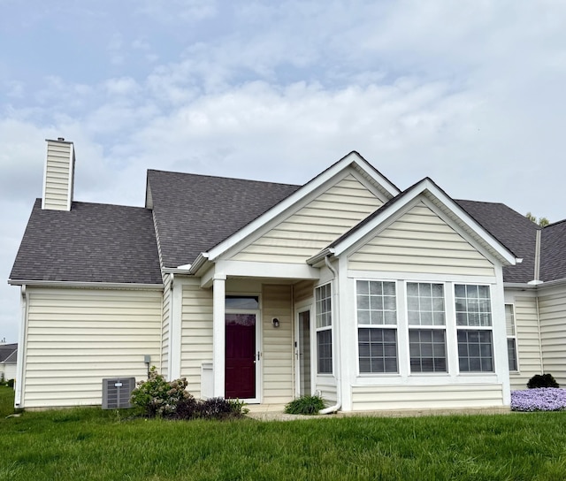 view of front of home with a shingled roof, a chimney, and a front lawn