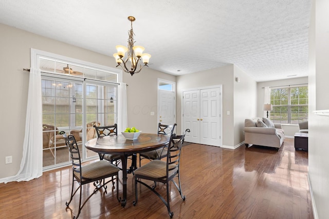 dining room with a textured ceiling, baseboards, wood finished floors, and a chandelier