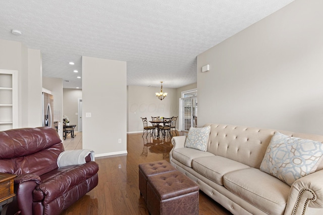 living room with light wood-style floors, a textured ceiling, baseboards, an inviting chandelier, and recessed lighting