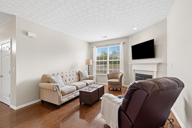 living room featuring a fireplace, a textured ceiling, and wood finished floors
