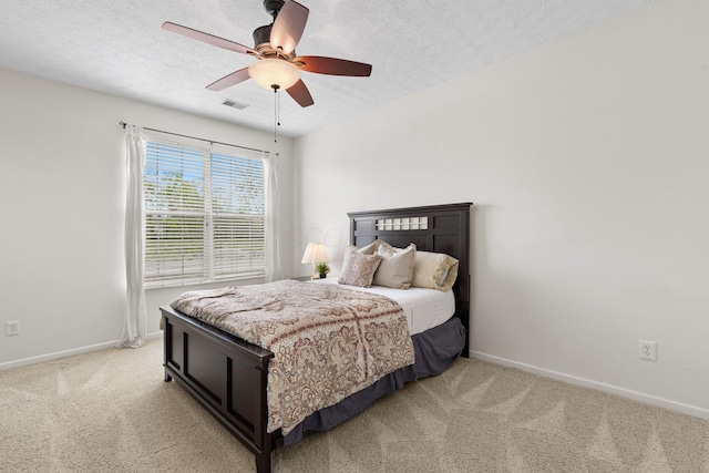 bedroom featuring visible vents, a textured ceiling, baseboards, and light carpet