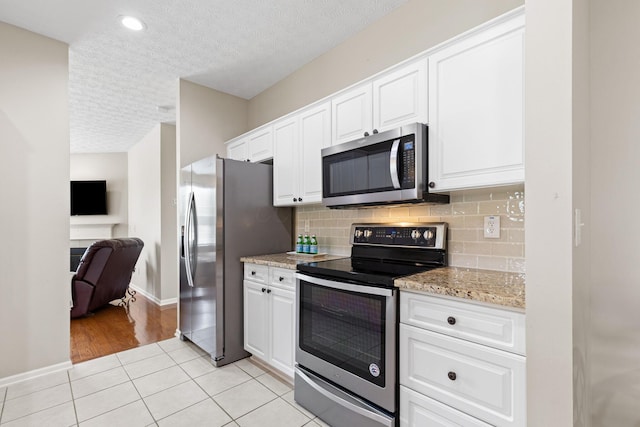 kitchen featuring appliances with stainless steel finishes, white cabinets, backsplash, and a textured ceiling