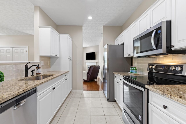 kitchen featuring a sink, appliances with stainless steel finishes, a textured ceiling, and white cabinetry