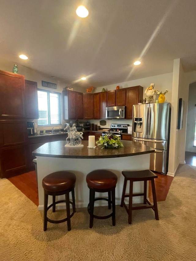 kitchen featuring dark colored carpet, stainless steel appliances, and a kitchen bar