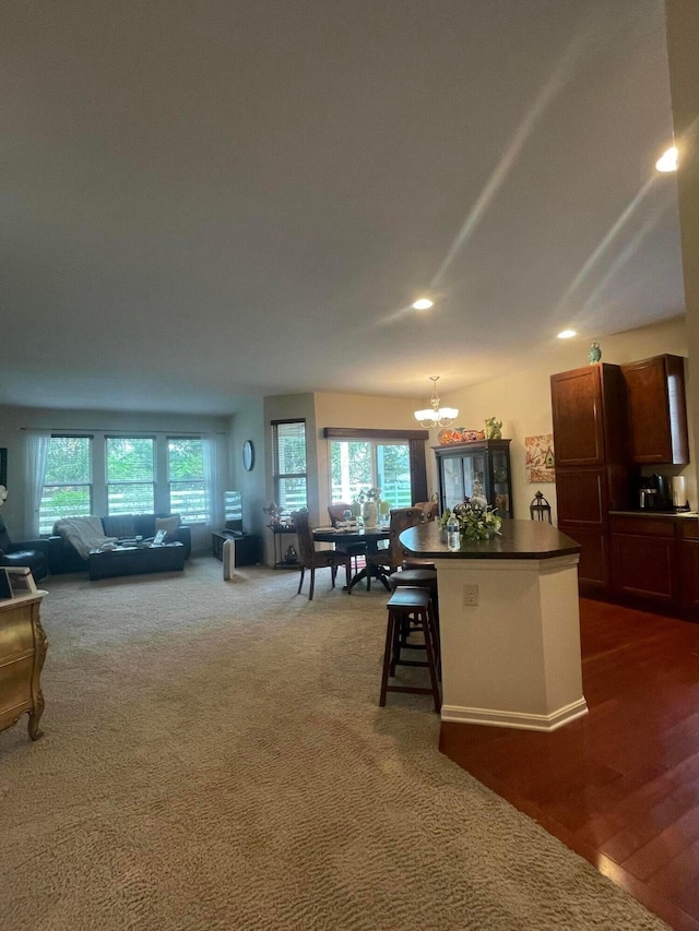 kitchen with an inviting chandelier, a kitchen island, dark countertops, open floor plan, and a kitchen breakfast bar