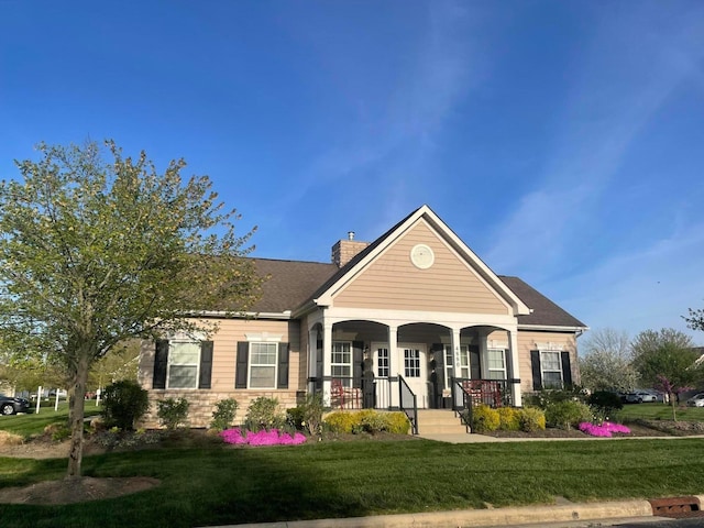 view of front of property with a chimney, a porch, and a front yard