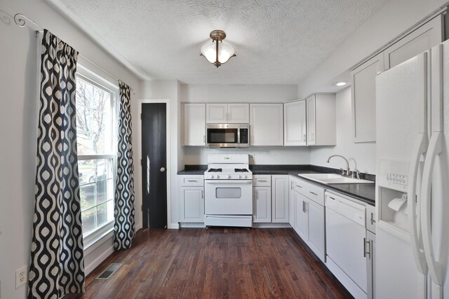 38 Ravine Ridge Dr S, Powell, OH 43065 - kitchen featuring dark wood-style floors, dark countertops, visible vents, a sink, and white appliances