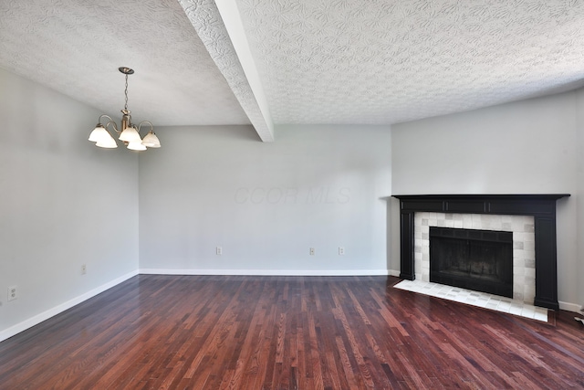 38 Ravine Ridge Dr S, Powell, OH 43065 - unfurnished living room featuring baseboards, an inviting chandelier, wood finished floors, and a tiled fireplace