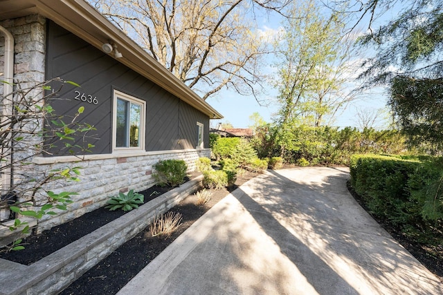 view of side of home with stone siding and a patio