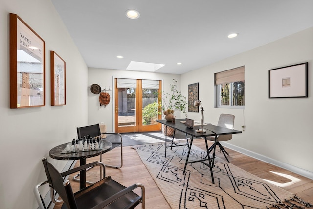 dining room featuring baseboards, recessed lighting, light wood-style flooring, and a skylight