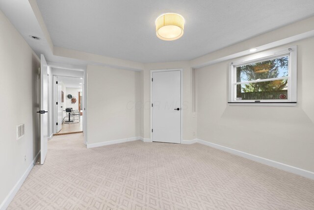 unfurnished room with baseboards, visible vents, and light carpet
