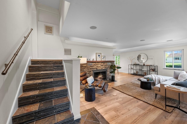 living room with plenty of natural light, visible vents, a stone fireplace, and stairway