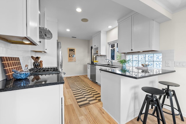 kitchen with a peninsula, tasteful backsplash, light wood finished floors, and recessed lighting