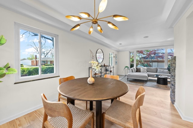 dining room featuring light wood-type flooring, plenty of natural light, baseboards, and a chandelier