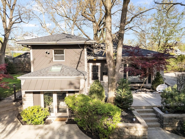view of front of home featuring brick siding, french doors, roof with shingles, and fence