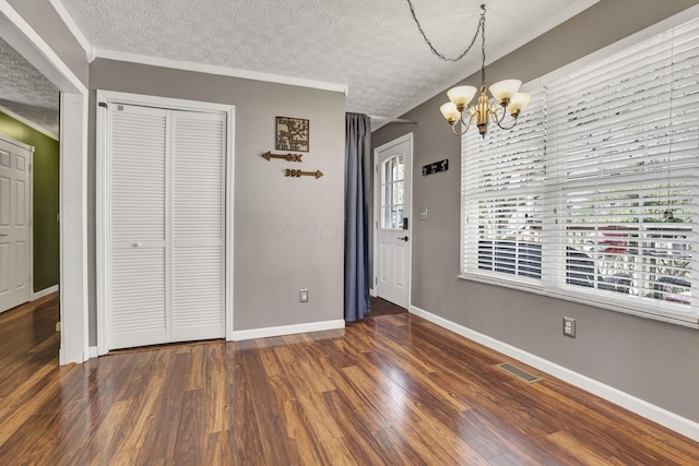 unfurnished dining area featuring visible vents, an inviting chandelier, baseboards, dark wood-style floors, and a textured ceiling