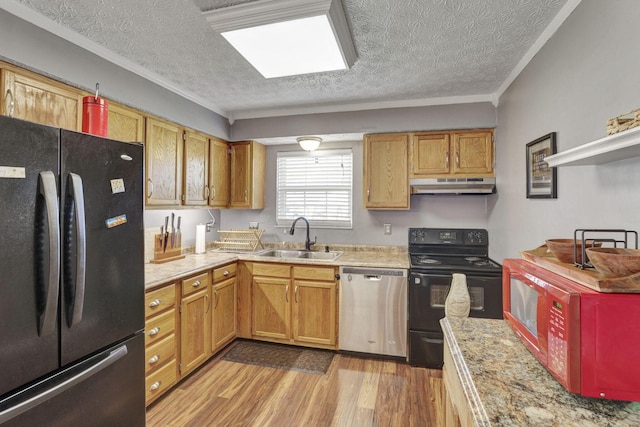 kitchen with light wood-style floors, a textured ceiling, under cabinet range hood, a sink, and black appliances