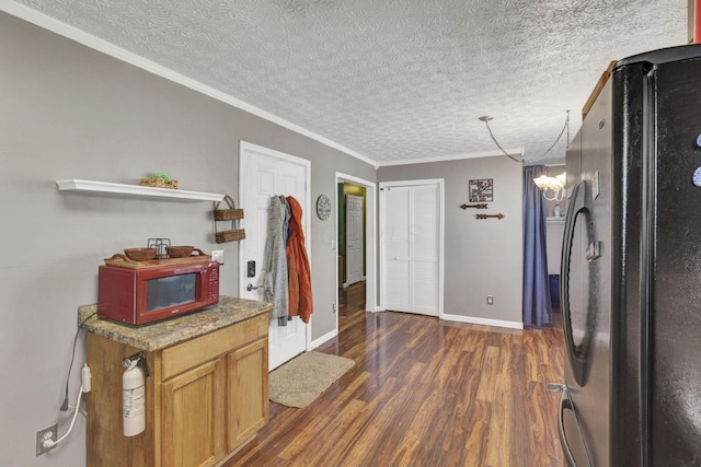interior space featuring an inviting chandelier, a textured ceiling, dark wood finished floors, freestanding refrigerator, and baseboards
