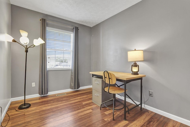 office with visible vents, a textured ceiling, baseboards, and dark wood finished floors