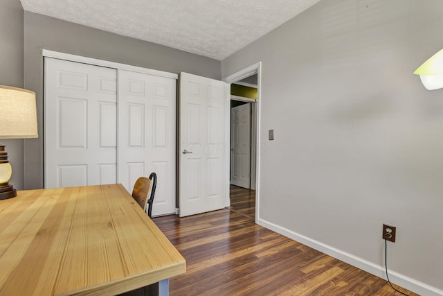 home office featuring baseboards, a textured ceiling, and dark wood-type flooring