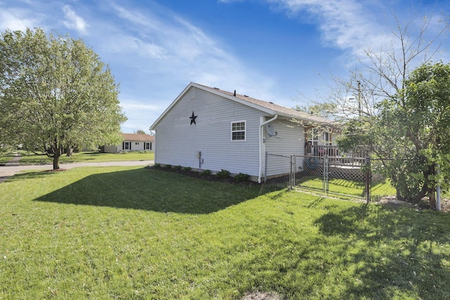 view of side of home with a gate, fence, and a yard