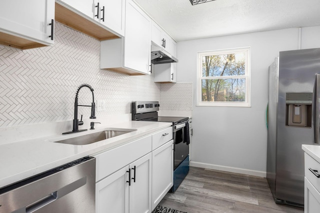 5930 Parkglen Rd, Galloway, OH 43119 - kitchen featuring wood finished floors, a sink, appliances with stainless steel finishes, light countertops, and under cabinet range hood