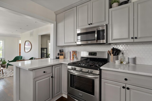 1345 Haines Ave, Columbus, OH 43212 - kitchen with appliances with stainless steel finishes, a peninsula, light countertops, decorative backsplash, and gray cabinetry