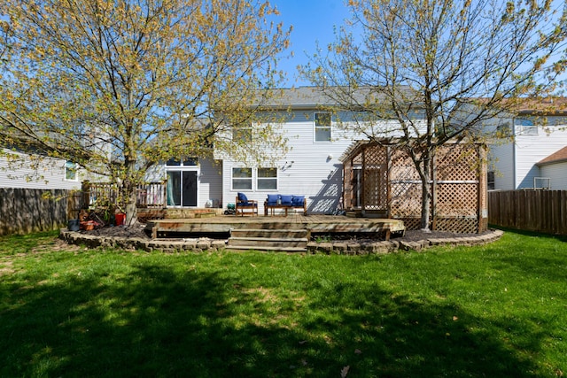 rear view of house featuring a wooden deck, a yard, and a fenced backyard